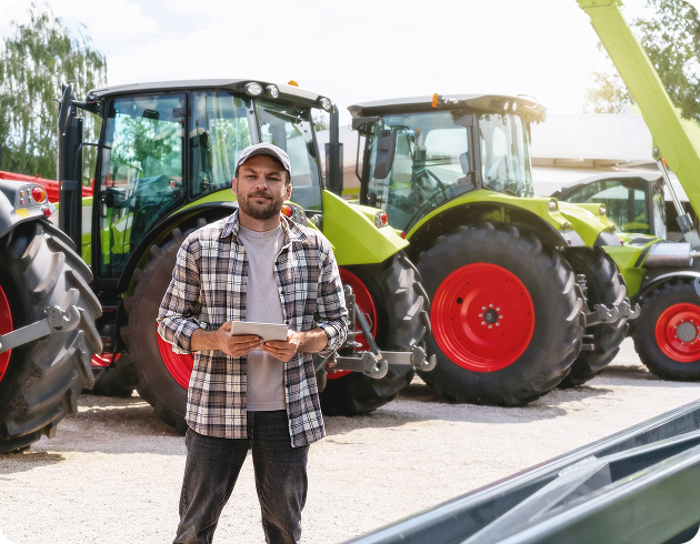 Man with tablet standing in front of large tractors