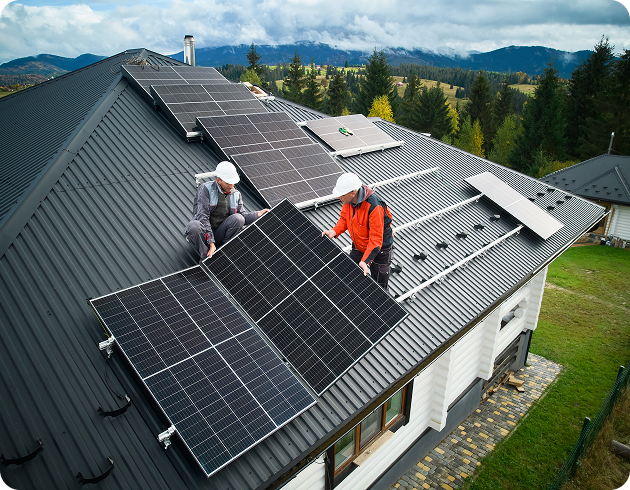 Two men in hardhats installing solar panel on roof of house