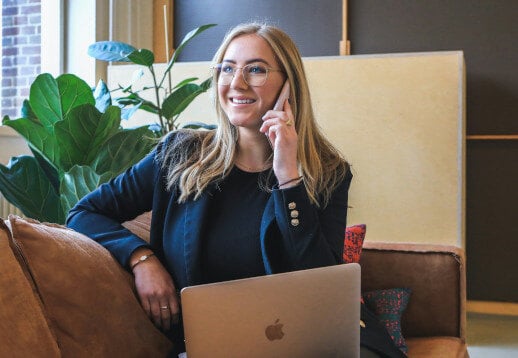 Young professional woman on cell phone with laptop resting on her lap